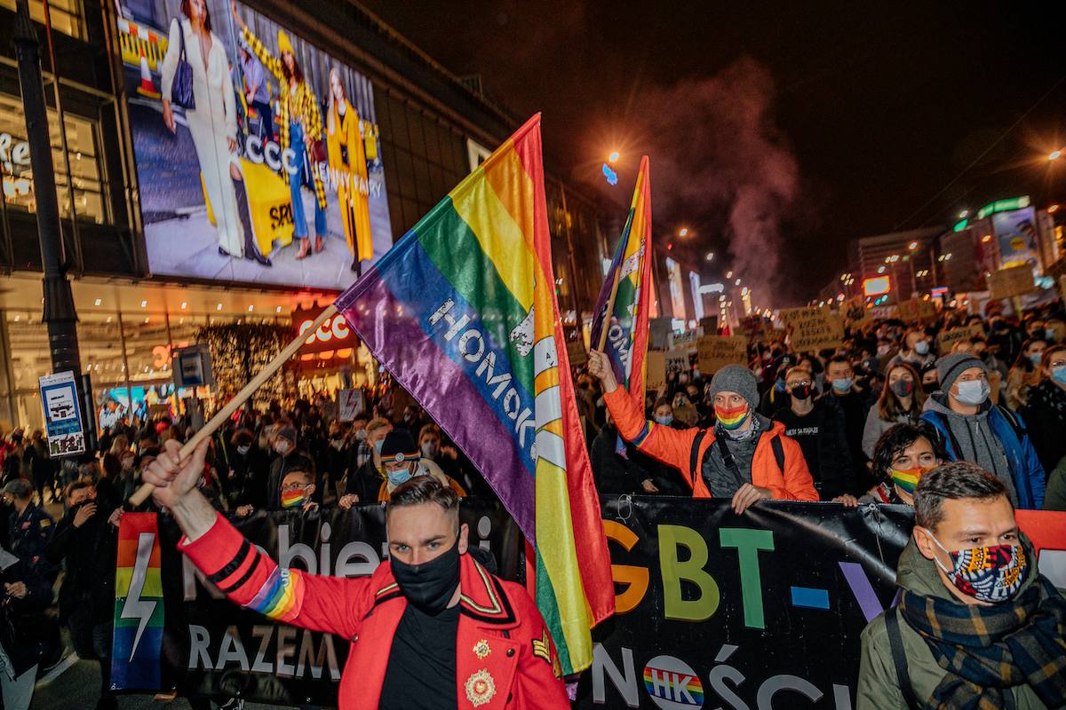 LGBTI activist Linus Lewandowski (in the background with a grey hat and rainbow face mask) marches during an anti-government protest in Warsaw on 30 October 2020. (Marcin Oliva Soto)